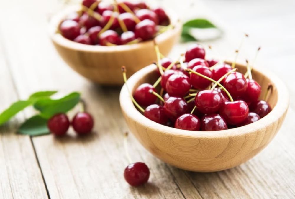 Two wooden bowls of red, fresh, juicy, tasty and healthy cherries on a wooden table