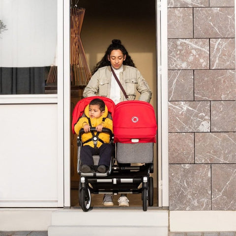 Woman pushing Bugaboo Donkey3 Duo with two children through doorway