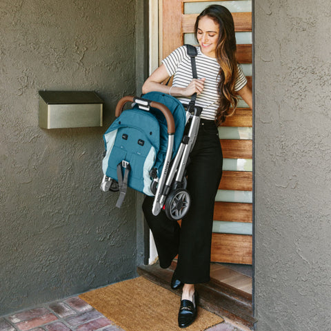 Woman carrying folded Minu stroller out the door of her home