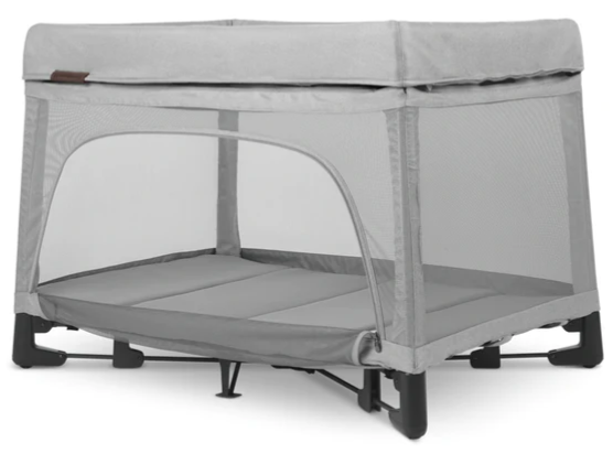 the uppababy remi travel crib in light grey with the zippered wall panel open, on a studio white background