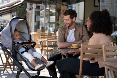 Man and woman at an outdoor cafe looking at toddler in Silver Cross Coast