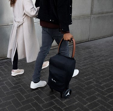 Man and woman walking together rolling folded Silver Cross Jet 2020 Stroller along with them