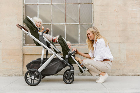 Woman crouching to interact with toddler in UPPAbaby rumbleseat