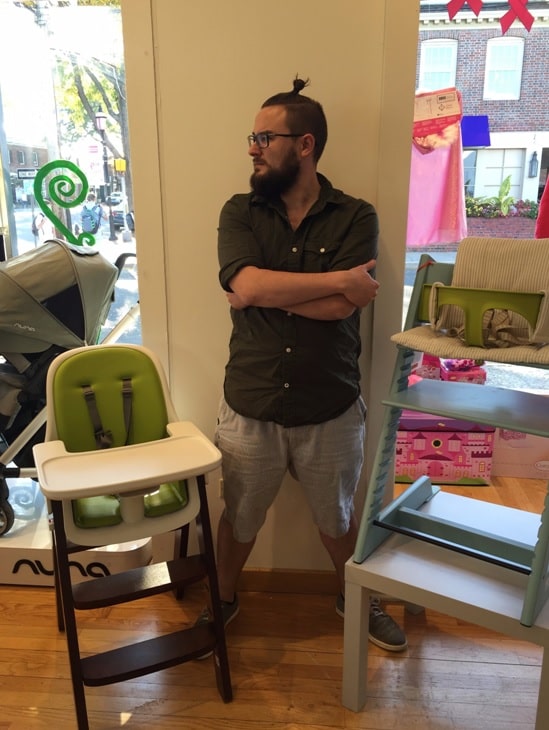 kyle from magic beans fairfield poses with oxo sprout high chair and stokke tripp trapp high chair