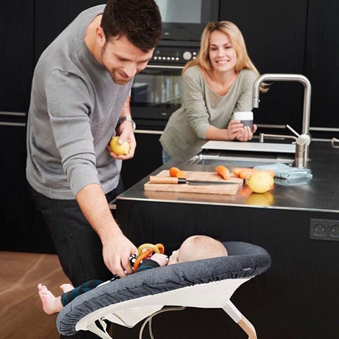 Man interacts with baby in grey Nomi Baby at the kitchen counter