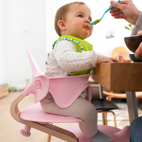 Child being fed in a pink Nomi High chair