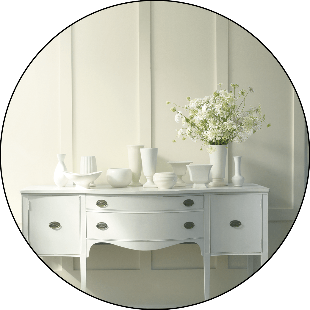 A white painted wall with white furniture and flowers in front of it