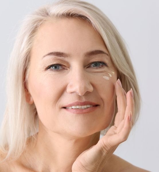 Image of a mature woman applying CameLife Restorative Serum. Camel milk skincare. 