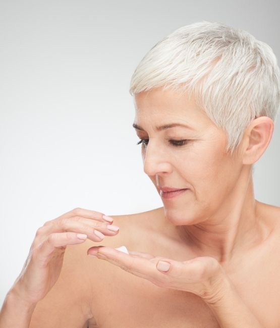 Mature woman treating her dry skin with CameLife Nourishing Body Mousse