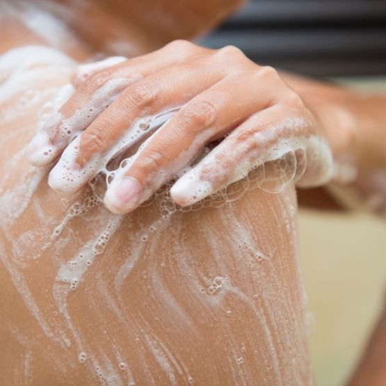 Image of a woman washing here aching shoulder with soap 