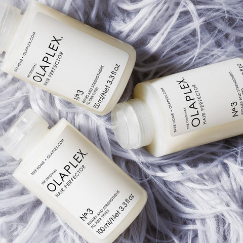 Three bottles of Olaplex Number 3 Hair Perfector on a shaggy lilac rug