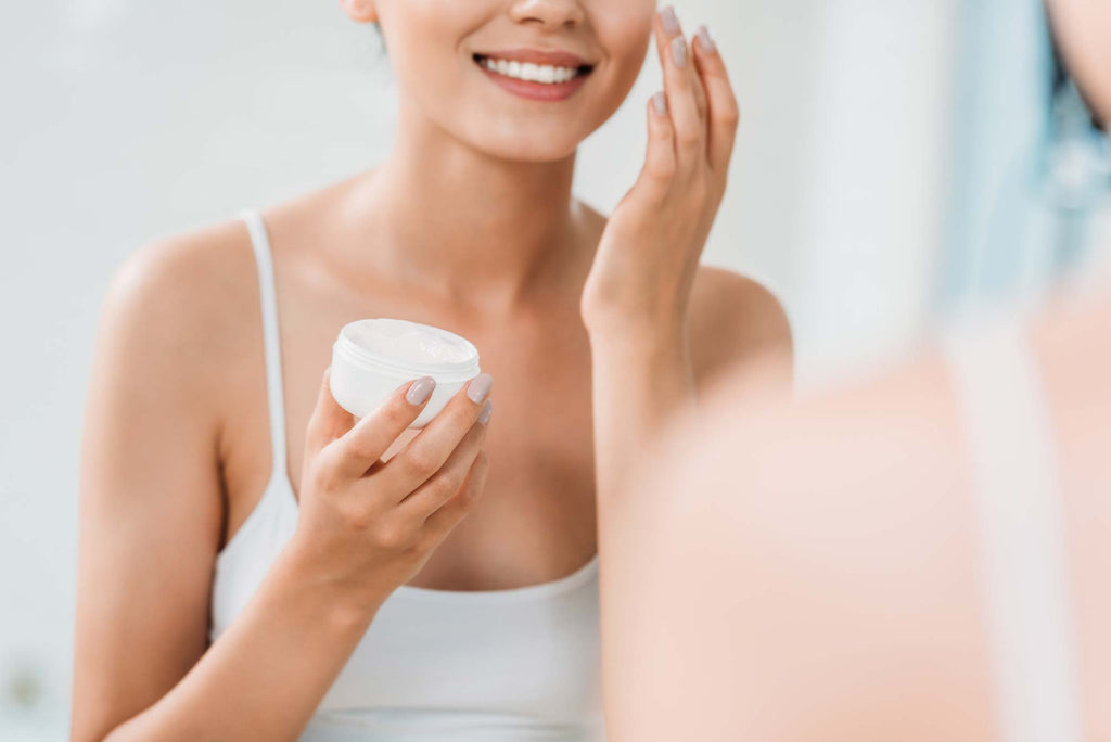 Woman applying skincare cream from a jar