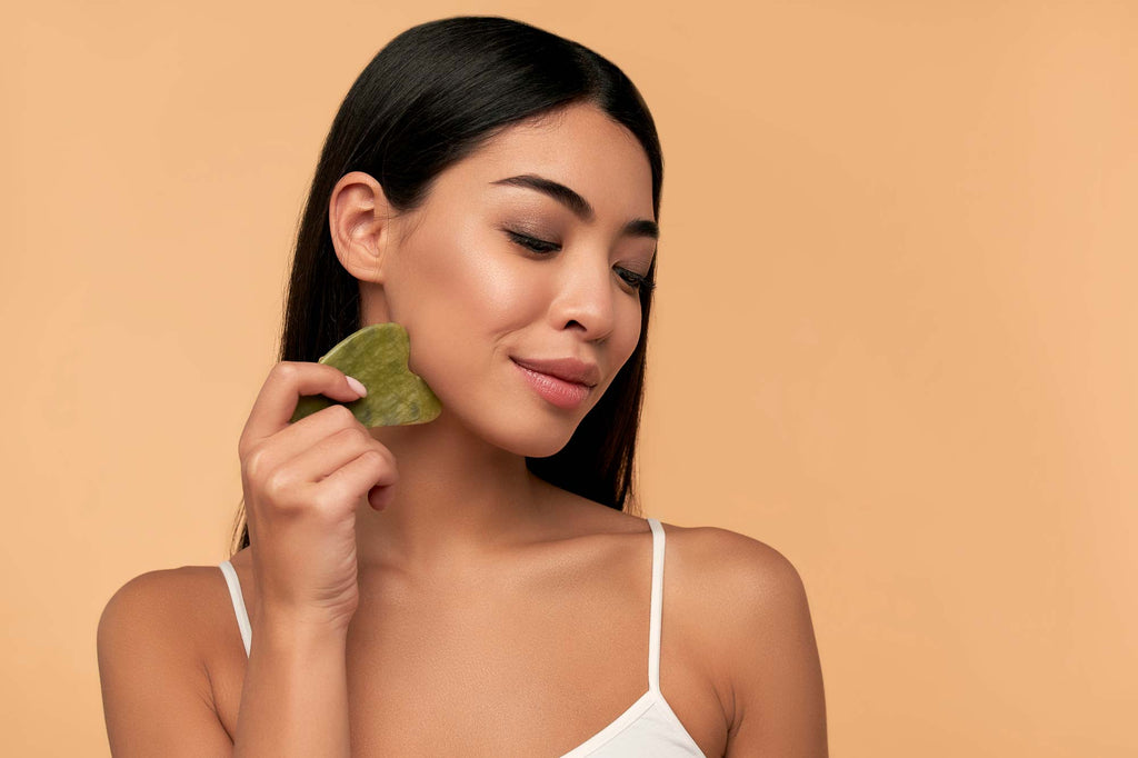Woman using gua sha on her face