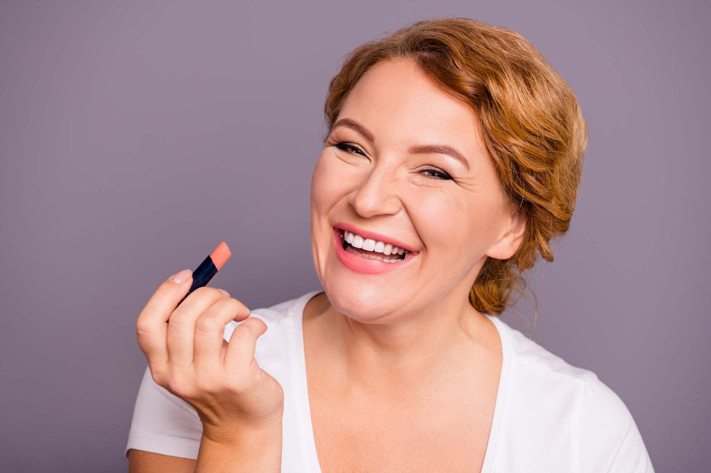 Woman applying lipstick and smiling 