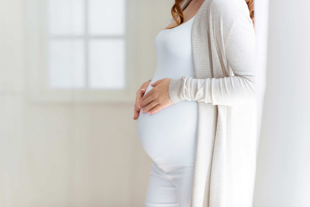 Woman wearing white holding pregnant belly