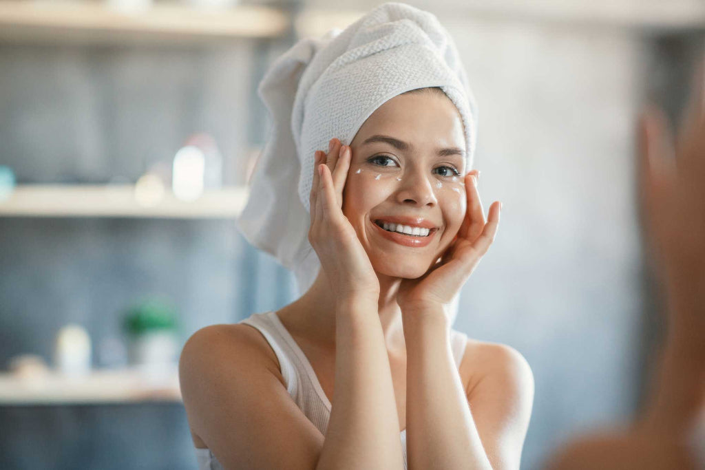 Woman with towel on her head applying eye cream