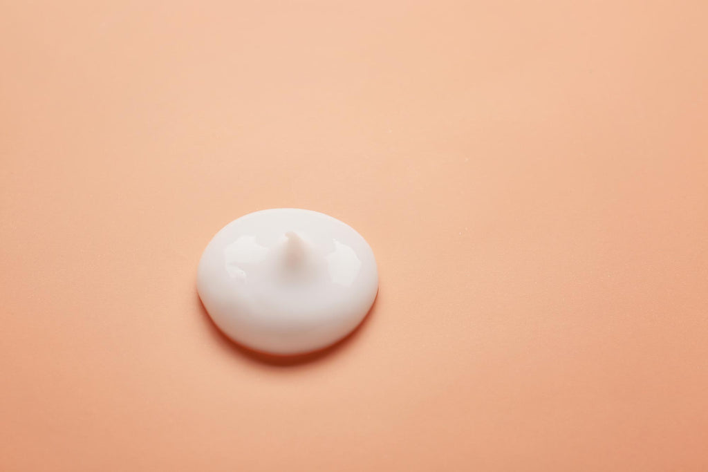 Dollop of white retinol cream on orange background