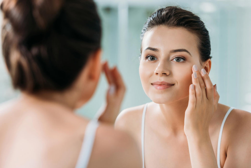 Woman smiling and applying skincare in mirror