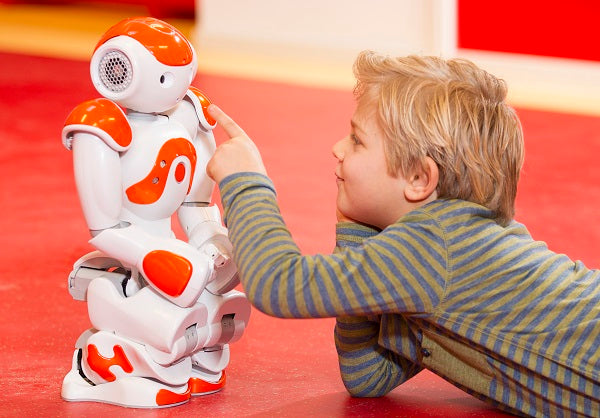 Photo of a child playing with a humanoid robot
