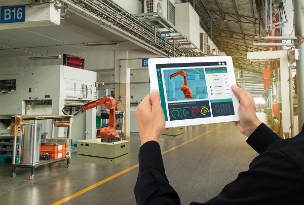 Photo of industrial engineer using the software on a tablet to monitoring robot arm in automotive manufacturing