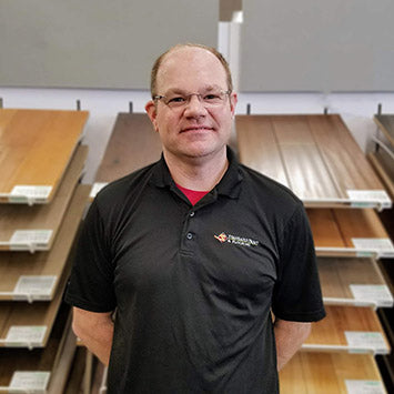 Jeff Rock wearing a black polo shirt and standing in front of hardwood flooring at Standard Paint & Flooring's West Valley Yakima, WA location.
