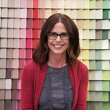 Marissa Tegen smiling in front of a wall of paint color chips at Standard Paint & Flooring's West Valley Yakima location.