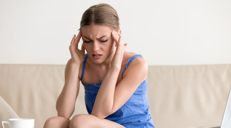 woman bent over with her hands on her temples looking stressed out