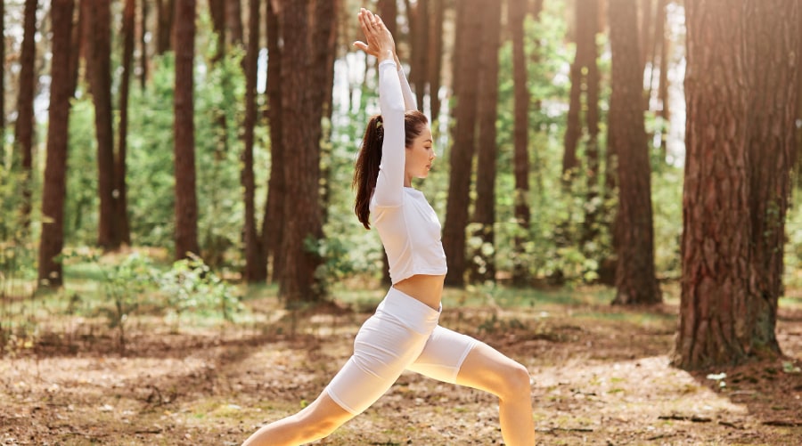 Frau im Wald auf einer Yogamatte, die hart trainiert