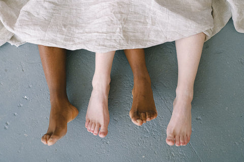 Couple's feet under bed sheets