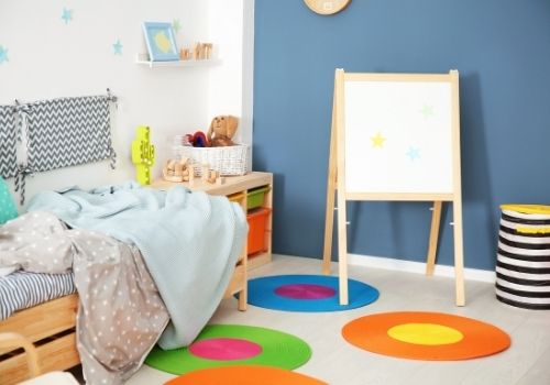Kids room painted with a blue/gray accent wall and many pop of colour.