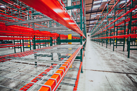 Rows of green pallet racking with orange cross beams and wire shelving at a warehouse install job