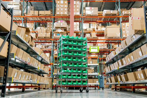 A bin cart sits between two rows of inventory in a warehouse