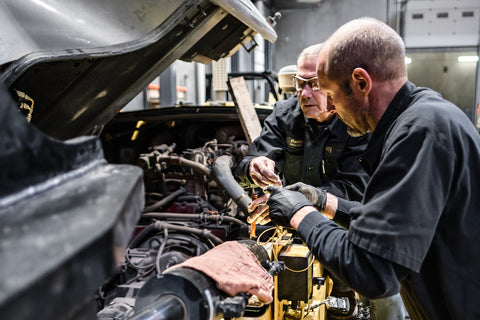 Two mechanics work on a forklift to make repairs