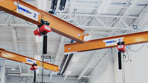 A set of overhead cranes on swing arms in a warehouse