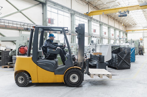 Happy man on a yellow forklift in a warehouse