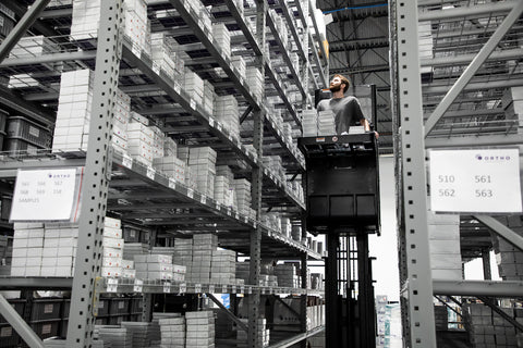 Warehouse employee picks items from an upper shelve using a stock picker