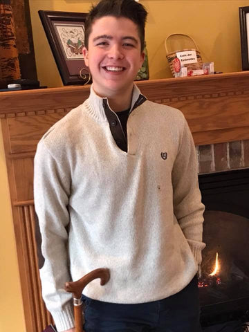 Mitchell Herndon, standing and smiling in front of a fireplace.