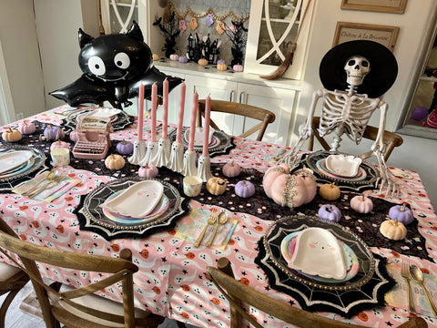 pastel halloween birthday party with skeleton and bat balloon. Table has ghost plates and pink ghost table cloth