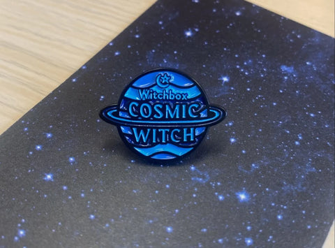 Blue badge in the shape and Saturn that reads 'Cosmic Witch'