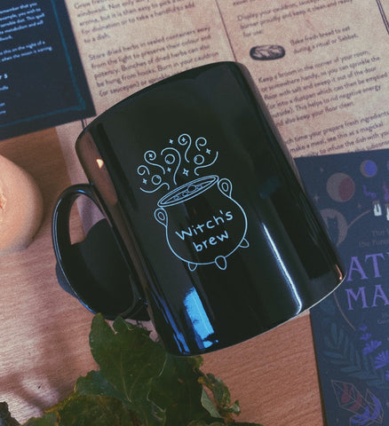 Black mug with white design of a cauldron that reads Witch's brew