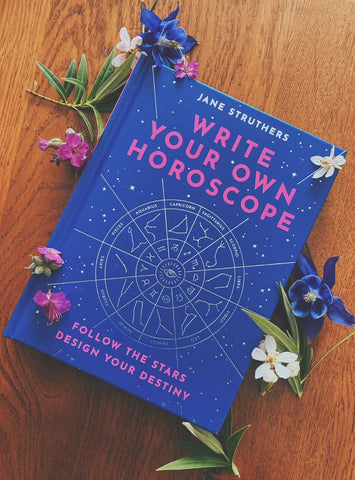 write your own horoscope book by Jane struthers - blue book on wooden table