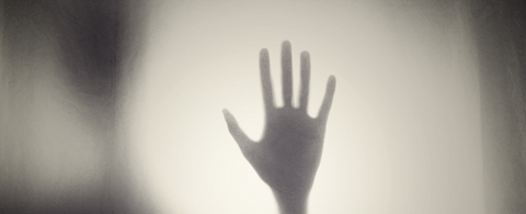 hand silhoutte behind glass foggy