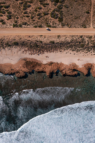 Top down of van driving along dusty coastal road