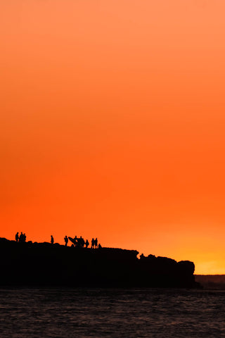 Silhouettes against bright orange sunset at Red Bluff