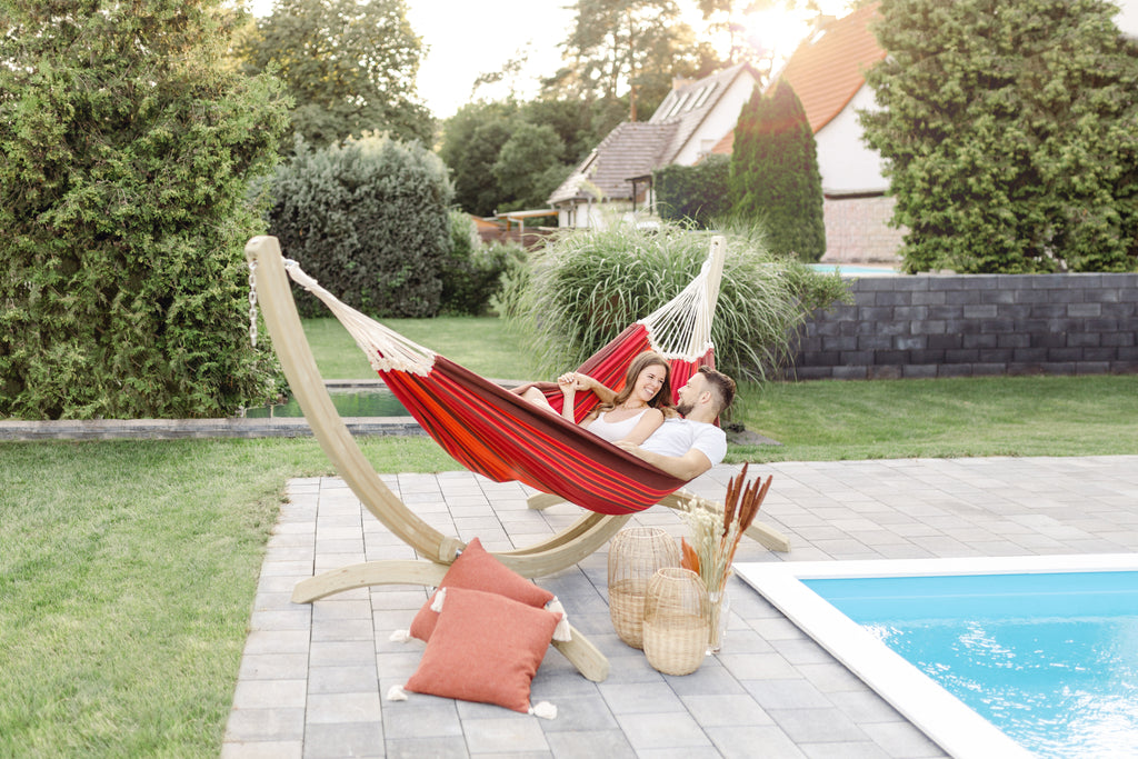 A man and Woman in a red hammock by a pool.