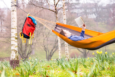 Man reading a book lay on a hammock