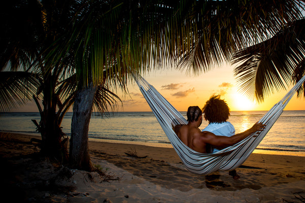 A couple in a Brasilia Cappucino Hammock staring out into the sunset.