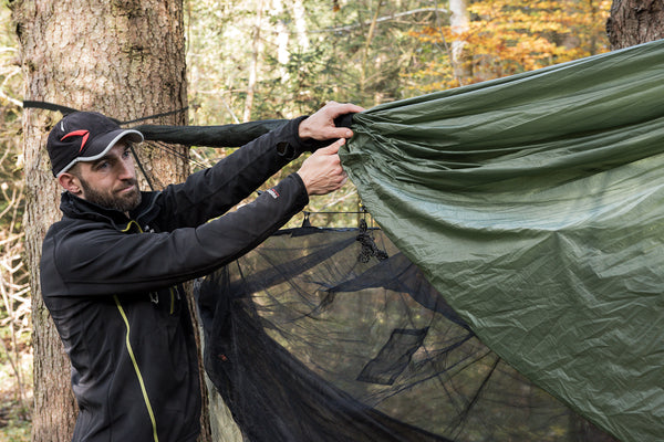 Man securing an Amazonas Tarp Sock to his tarp