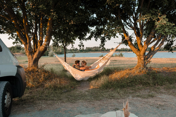 A couple sitting in a Rio Boho hammock in between two trees