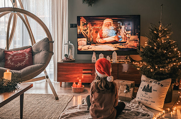 A child sitting next to a Globo chair, watching TV at Christmas